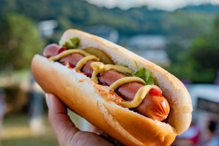 Show someone holding a keto hot dog bun filled with a delicious hot dog, capturing the indulgence of the classic treat.